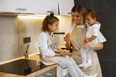 Güzel bir kadın ve önlüklü küçük tatlı kızı birbirlerine bakıp kruvasanlarını tadarken gülümsüyorlar.