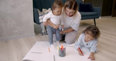 Anne ve kızları evde kağıda çizim yapıyorlar.