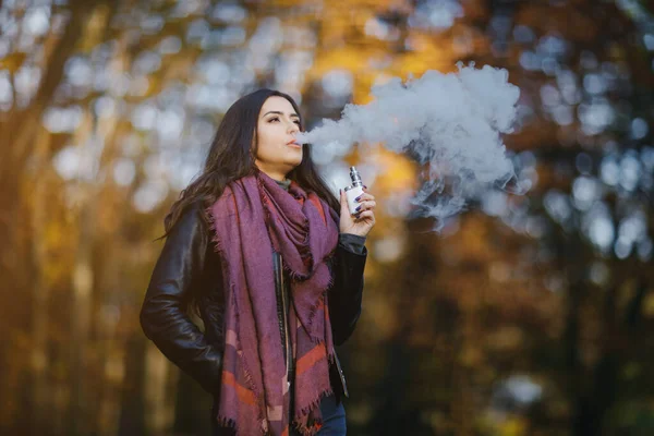 Menina morena está fumando um e-cigarro — Fotografia de Stock