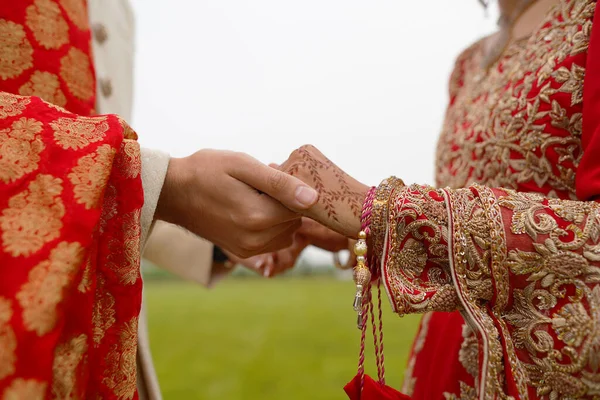 hindu bride walks behind husband holding garb