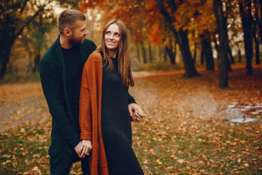 Zarif çift sonbahar parkında vakit geçiriyor.