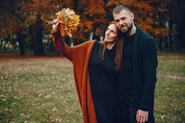 Zarif çift sonbahar parkında vakit geçiriyor.