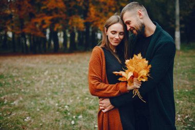 Zarif çift sonbahar parkında vakit geçiriyor.