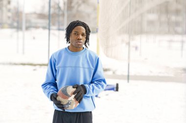 Afrika kökenli Amerikalı adam kış günü futbol oynuyor.