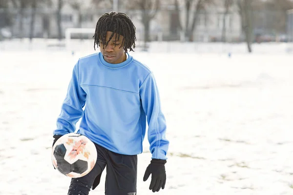 Hombre afroamericano jugando al fútbol en el día de invierno — Foto de Stock