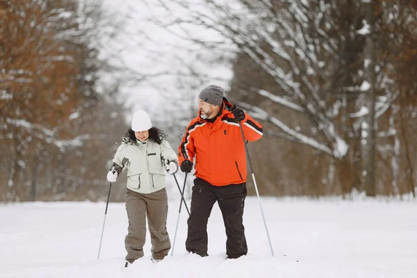 Senior couple skiing cross-country in a forest