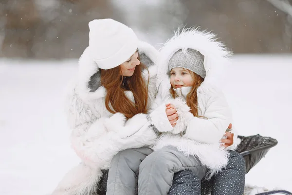 Madre e bambino in abiti invernali giocano nel parco invernale — Foto Stock