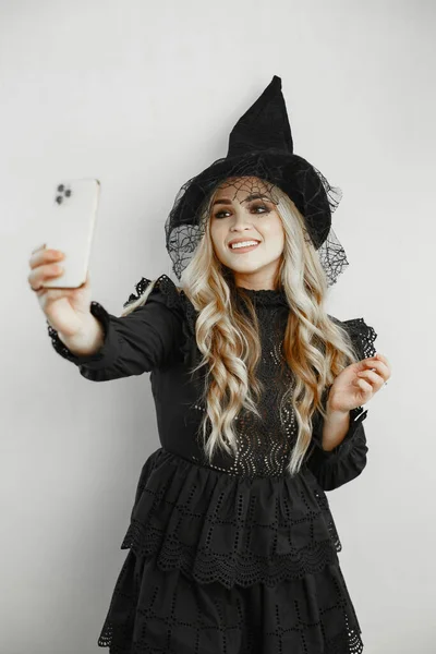 Uma mulher vestida de preto. Senhora com maquilhagem de Halloween. Menina em um fundo branco. — Fotografia de Stock