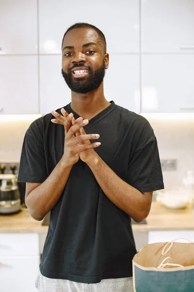 Uomo afro-americano in una cucina vicino a una borsa con cibo — Foto Stock