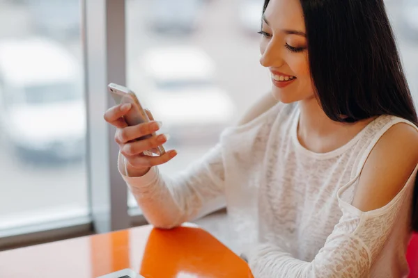 Hermosa chica joven disfruta del teléfono y la tableta — Foto de Stock