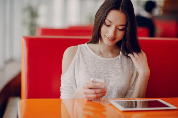 Hermosa chica joven disfruta del teléfono y la tableta — Foto de Stock