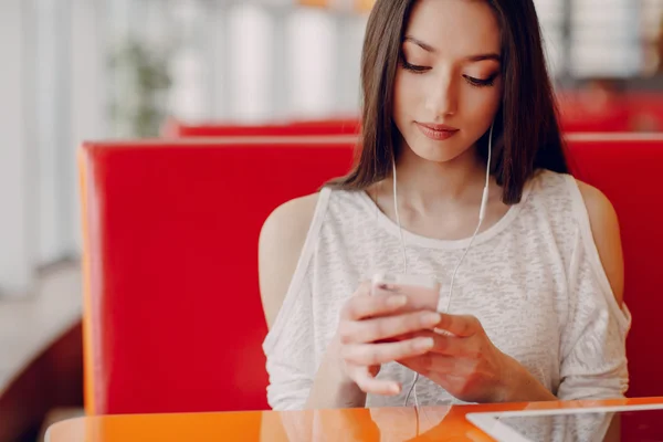 Hermosa chica joven disfruta del teléfono y la tableta — Foto de Stock