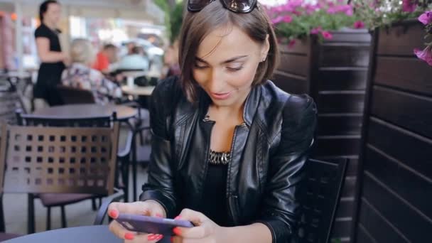Mooie brunette geniet gadget buitenshuis — Stockvideo