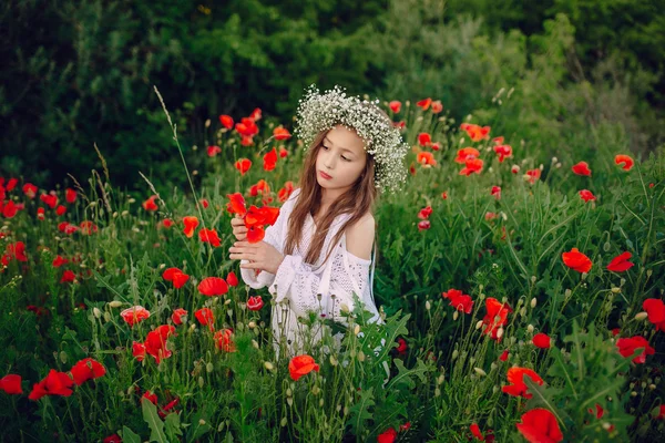 Schönes kleines Mädchen posiert in einem Rock-Kranz aus Mohn — Stockfoto