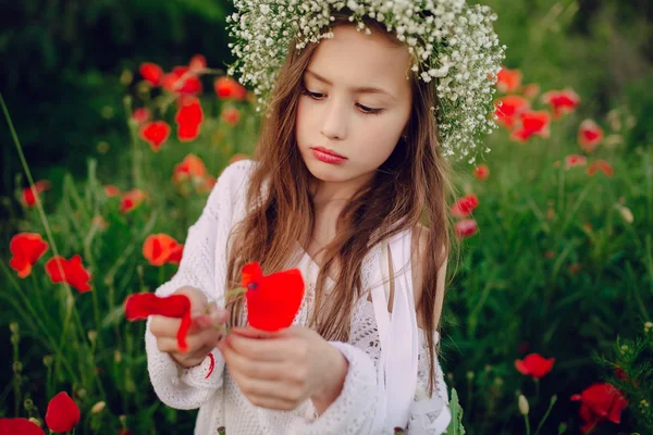 Gyönyörű kicsi lány pózol egy szoknya koszorú a pipacsok — Stock Fotó