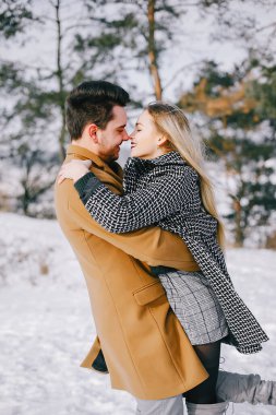 karlı bir günde parkta yürüyen mutlu genç çift