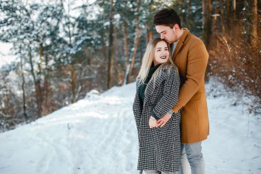 karlı bir günde parkta yürüyen mutlu genç çift