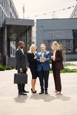 Modern ofis binasının önünde duran kendinden emin iş adamları. Erkekler ve kadınlar konuşuyorlar ve belgelere bakıyorlar. Bankacılık ve finans piyasası kavramı.