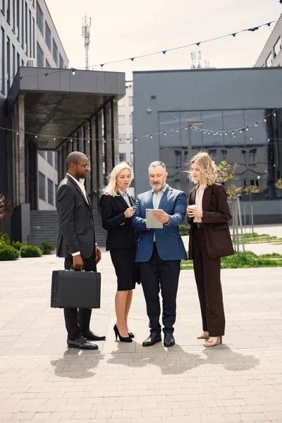 Modern ofis binasının önünde duran kendinden emin iş adamları. Erkekler ve kadınlar konuşuyorlar ve belgelere bakıyorlar. Bankacılık ve finans piyasası kavramı.