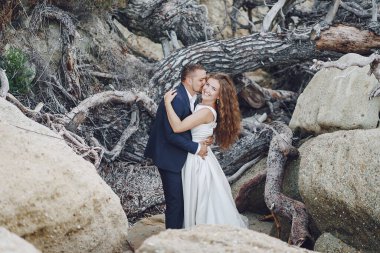 gri dalları yakınındaki genç kocasıyla beyaz elbiseli genç güzel uzun saçlı gelin