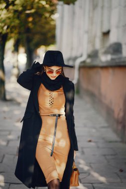 Şık bir kız sıcak bir sonbahar gününde şehirde yürüyor.