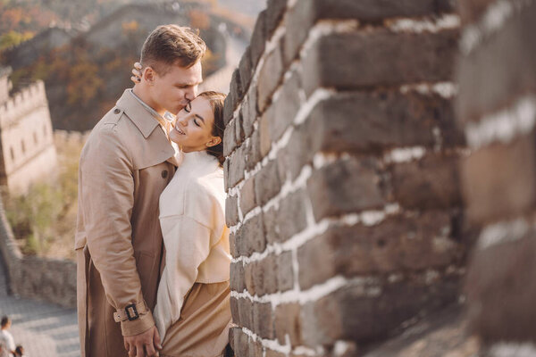 beautiful young couple hugging at the Great Wall of China. Newly married couple on their honemoon to Great Wall near Beijing China. Stylish couple exploring one of the wonders of the world.