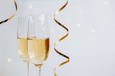 Beyaz arka plan tatilinde iki kadeh şampanya ve kurdele.