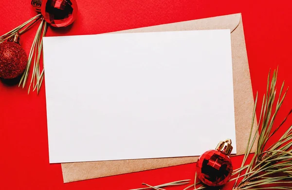 Kırmızı izole edilmiş arka planda köknar dalı ve oyuncağı olan boş bir noel notu. Yeni yıl konsepti