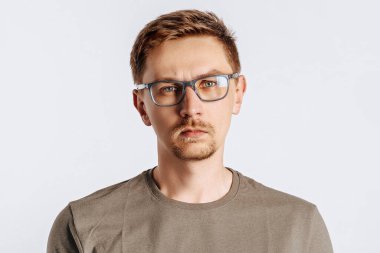 Sakallı, gözlüklü, genç ve yakışıklı bir adam beyaz, soyutlanmış arka plandan memnun değil.