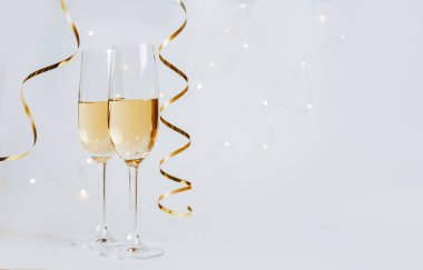 Beyaz arka plan tatilinde iki kadeh şampanya ve kurdele.
