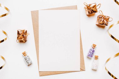 Zarflı boş not, hediyeler ve beyaz arka planda altın parıltılı yıldızlar.