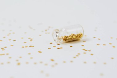 Altın ve gümüş bilezikler beyaz arka plandaki şişelerden saçılır.