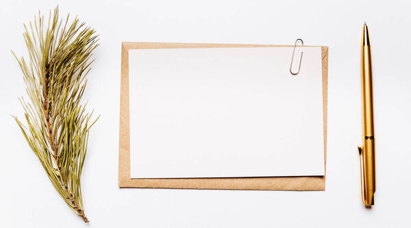 Blank note with envelope, spruce branch and gold pen on white background