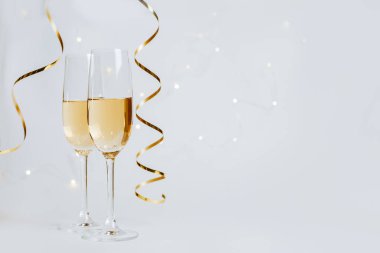 Beyaz arka plan tatilinde iki kadeh şampanya ve kurdele.