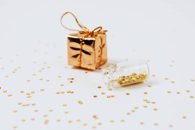 Altın ve gümüş bilezikler şişelerden saçılır ve beyaz arka planda bir hediye