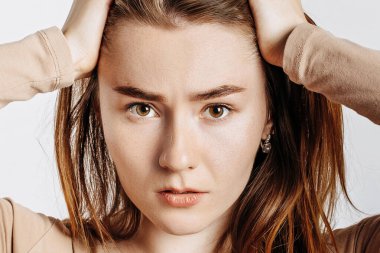 Korku içindeki güzel esmer kız başını izole edilmiş beyaz bir arka planda tutuyor. Kadın kötü haberle şoka girdi.