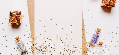 Zarflı boş not, hediyeler ve beyaz arka planda altın parıltılı yıldızlar.