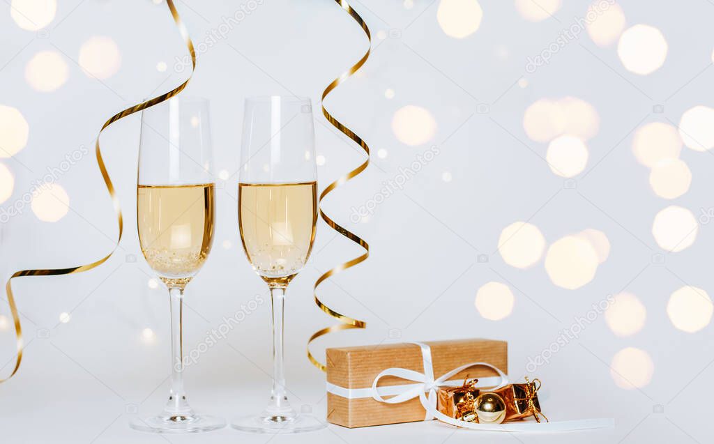 Two glasses of champagne with lights and ribbons on a white background holiday