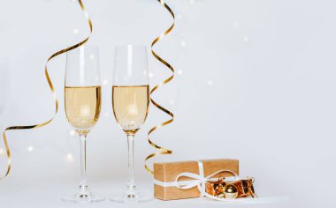 Beyaz arka plan tatilinde iki kadeh şampanya ve kurdele.