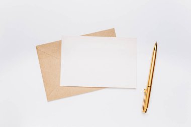 Zarflı boş not ve beyaz arkaplanda altın kalem