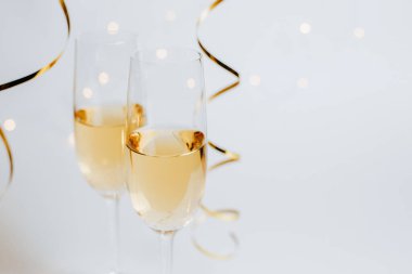 Beyaz arka plan tatilinde iki kadeh şampanya ve kurdele.