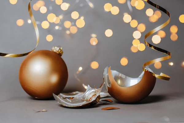 Kırık Noel oyuncağı, yeni yılı süslemek için koyu gri arka planda kurdeleler ve ışıklarla süslüyor.