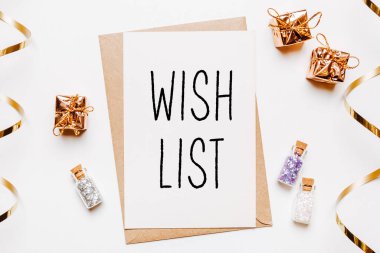 Dilek listesi notu, beyaz arka planda hediyeler ve altın parıltılı yıldızlar. Mutlu Noeller ve yeni yıl konsepti