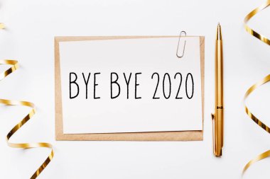 Güle güle 2020. Zarf, kalem, hediyeler ve beyaz arka planda altın kurdeleyle. Mutlu Noeller ve yeni yıl konsepti