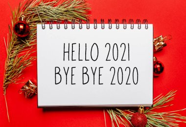 Merhaba 2021 güle güle 2020 yılbaşı notu. Kırmızı izole arka planda köknar dalı ve oyuncakla birlikte. Yeni yıl konsepti