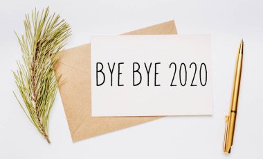 Güle güle 2020. Zarf, ladin dalı ve beyaz arka planda altın kalemle. Mutlu Noeller ve yeni yıl konsepti