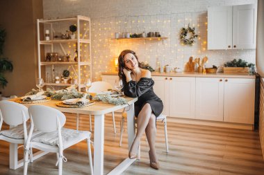 İki güzel, neşeli genç kız arkadaş yeni yıl mutfağının arka planındaki Noel sofrasına gülüyorlar.