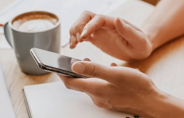 Adam iş yerindeki not defterine akıllı telefonuyla iş bilgileri yazıyor.