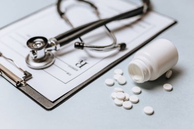 Beyaz haplar, steteskop, doktorun masasında reçete. Tıp konsepti. Tıbbi ürünlerin dozunu belirleme araştırması. Sağlık hizmeti ya da hastalık. Hastanede veya eczanede hap veya hap.