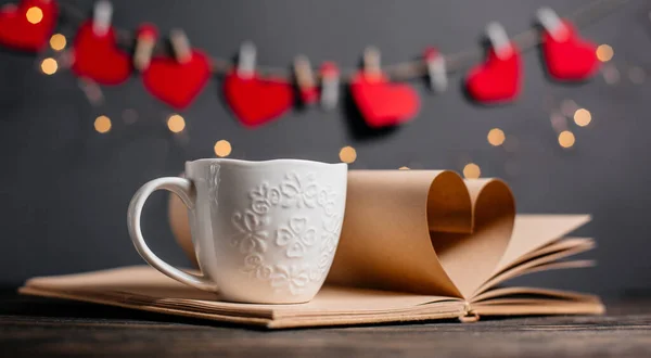 Heart made from book sheets with a cup, love and valentine concept on a wooden table